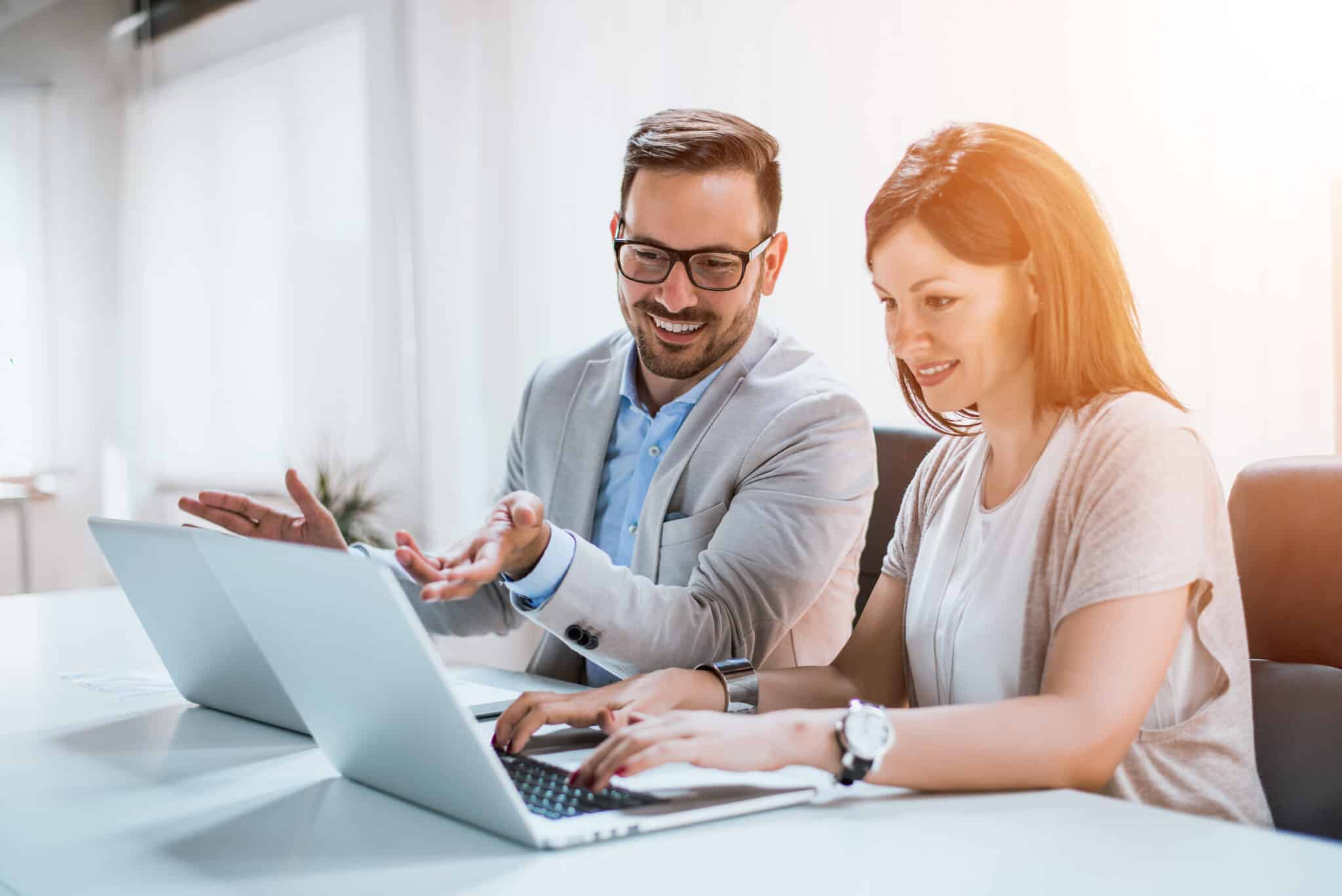 Zwei Mitarbeitende sitzen gemeinsam an Laptops und analysieren Daten – Symbol für kollaboratives Arbeiten und den gezielten Einsatz von Massnahmen zur Personalentwicklung.